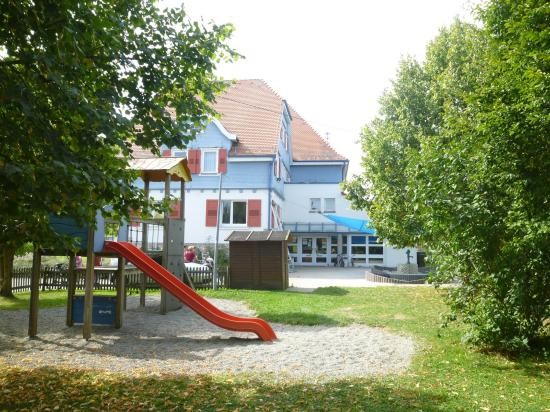 Kindergarten Brittheim Außenansicht, vor dem Gebäude ist ein Klettergerüst mit einer roten Rutsche zusehen