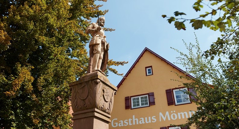 Statue mit Blick auf Gasthaus Mömpel